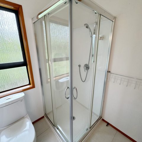 Glass shower enclosure in a bright bathroom with a window.