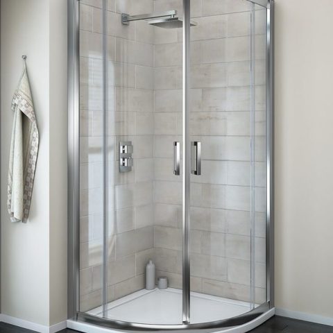 Modern glass shower enclosure with silver frame and beige tiled walls.