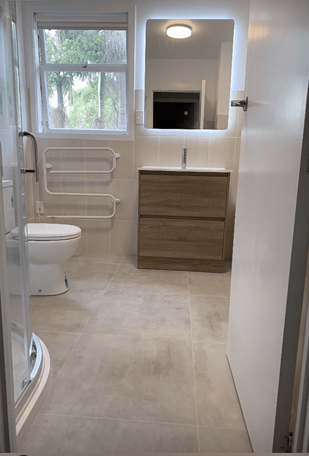 Modern bathroom with shower, toilet, and wooden vanity.
