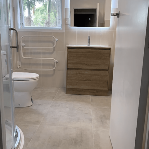 Modern bathroom with shower, toilet, and wooden vanity.