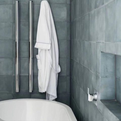 White towel hanging in a modern bathroom with gray tiles.