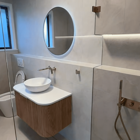 Modern bathroom with round mirror, glass shower, and freestanding bathtub.