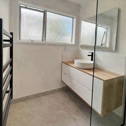Modern bathroom with sink, mirror, and frosted windows.