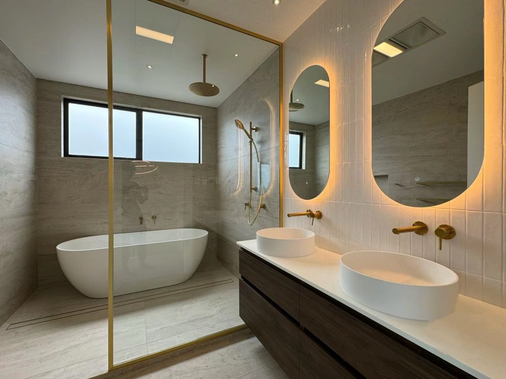 Modern bathroom with freestanding tub, double sinks, and illuminated mirrors.