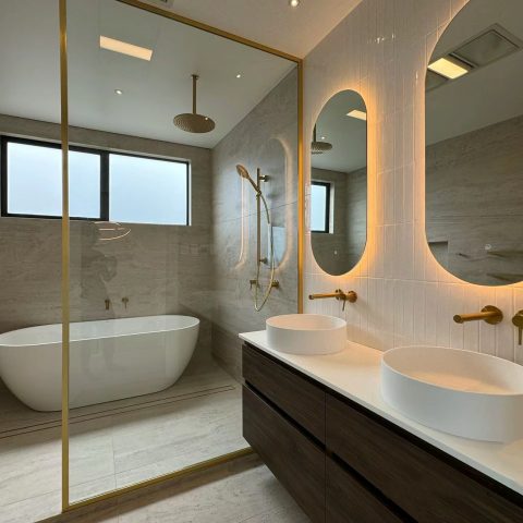Modern bathroom with freestanding tub, double sinks, and illuminated mirrors.