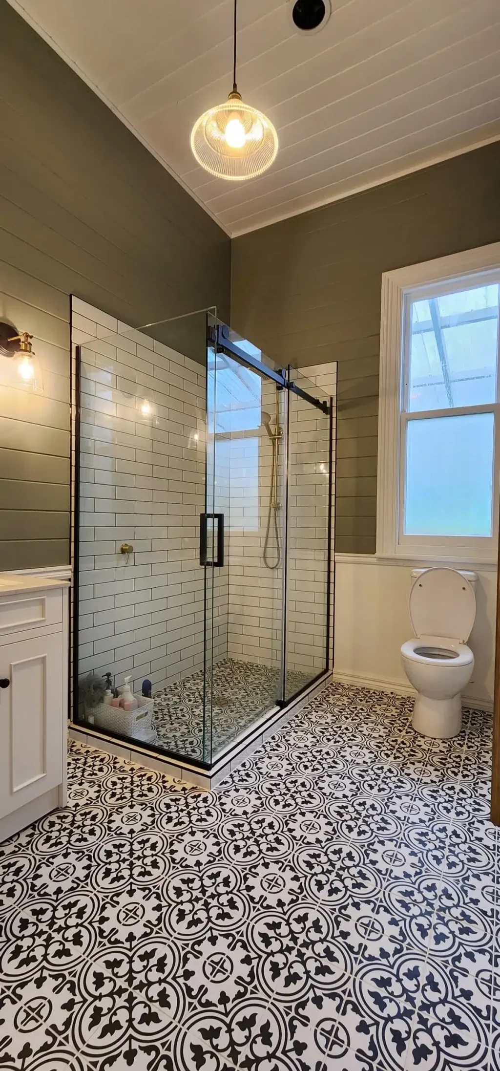 Modern bathroom with glass shower, white tiles, and patterned floor.