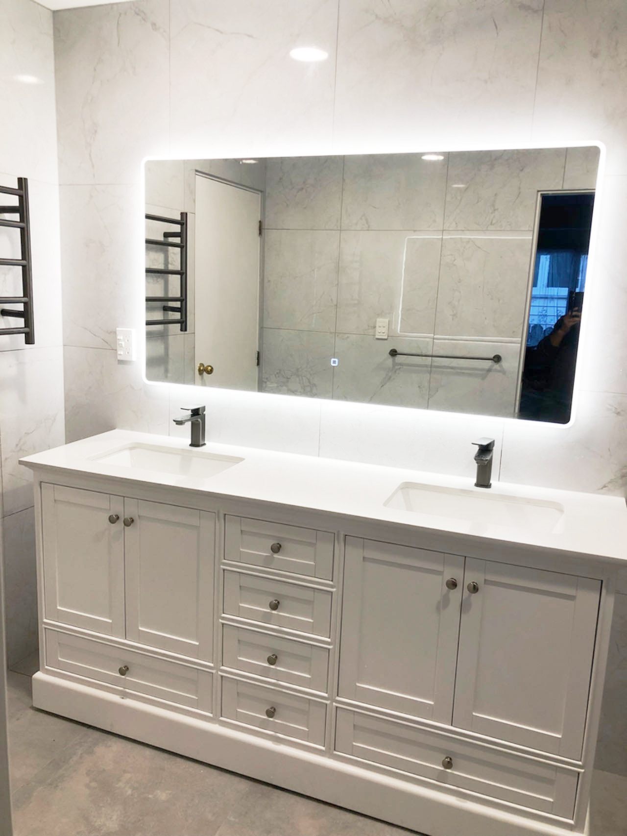 Modern bathroom with double sink vanity and illuminated mirror.