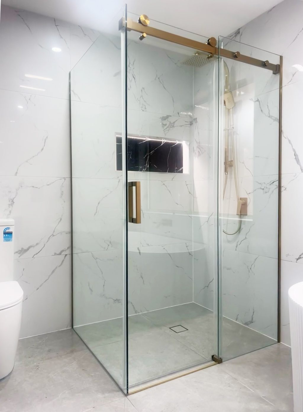 Modern bathroom with glass shower enclosure and marble walls.