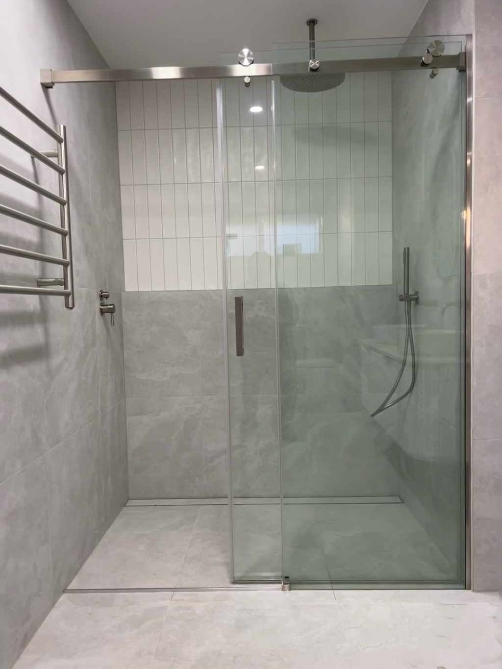 Modern bathroom with glass shower door and tiled walls.