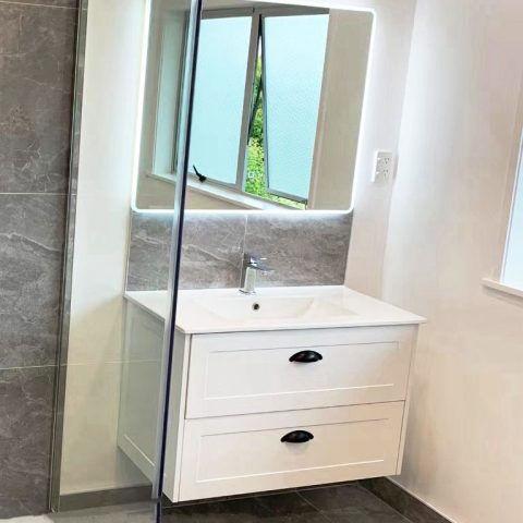 Modern bathroom with white vanity, mirror, and frosted window.
