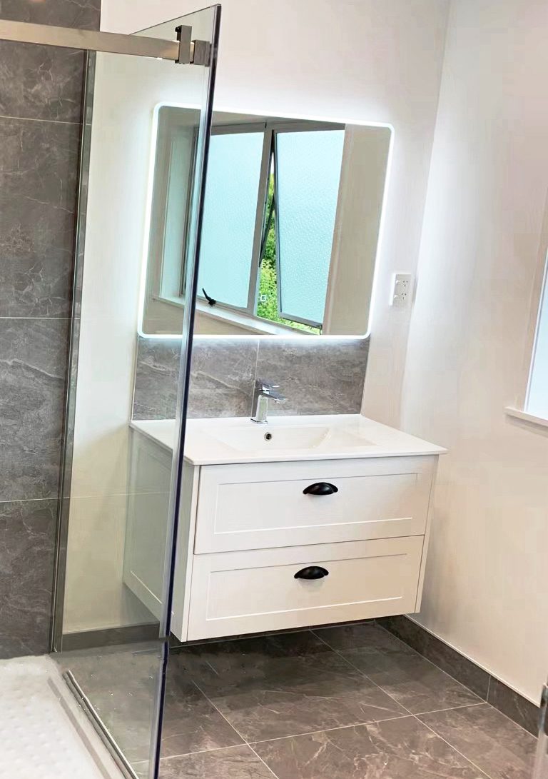 Modern bathroom with white vanity, mirror, and frosted window.