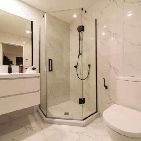 Modern bathroom with glass shower, white vanity, and toilet.