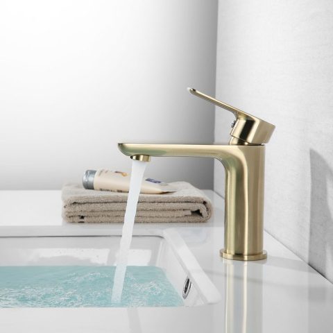 Gold faucet with running water filling a sink.