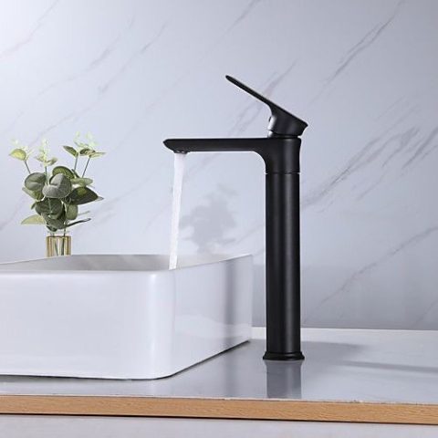 Black faucet with running water next to a white sink and plant.