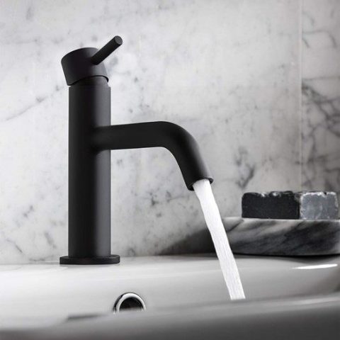 Black faucet with running water in a modern bathroom.