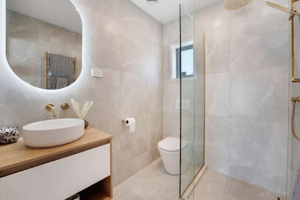 Modern bathroom with glass shower, sink, and toilet.