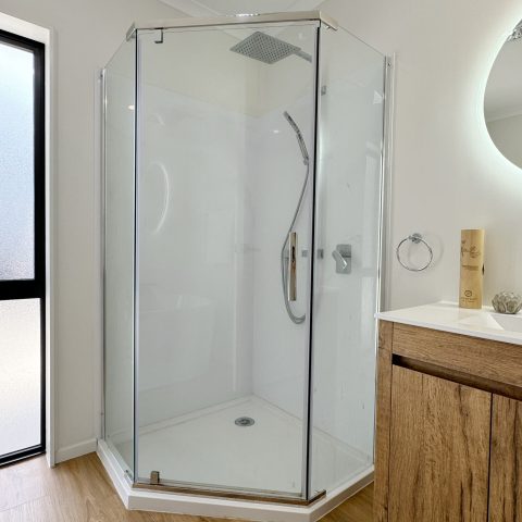 Glass shower enclosure with wooden vanity in modern bathroom.