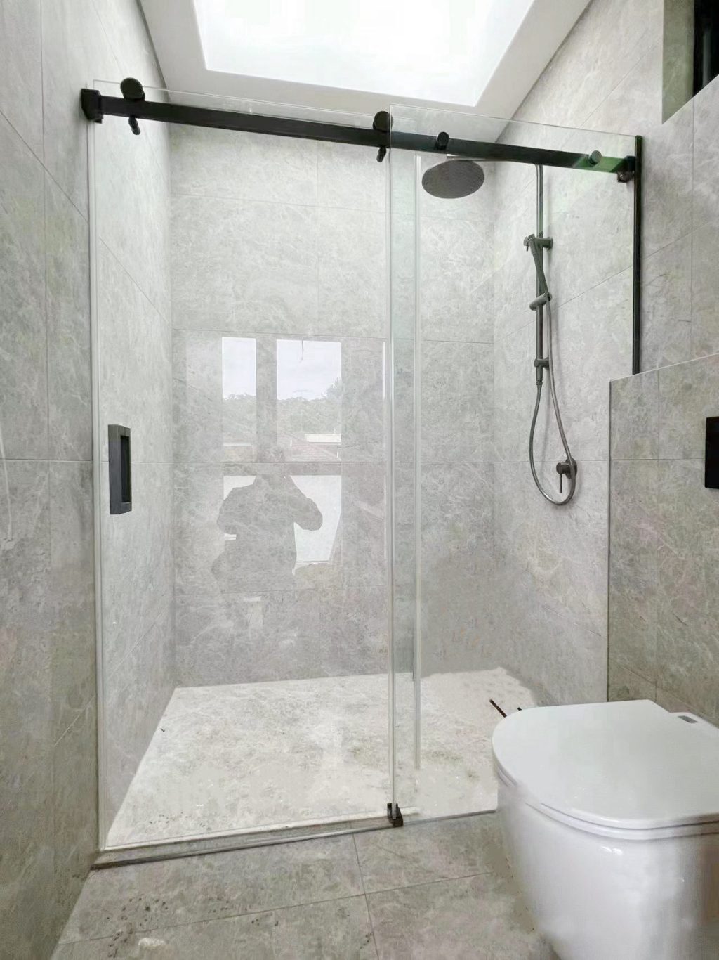Modern bathroom with glass shower door and overhead showerhead.