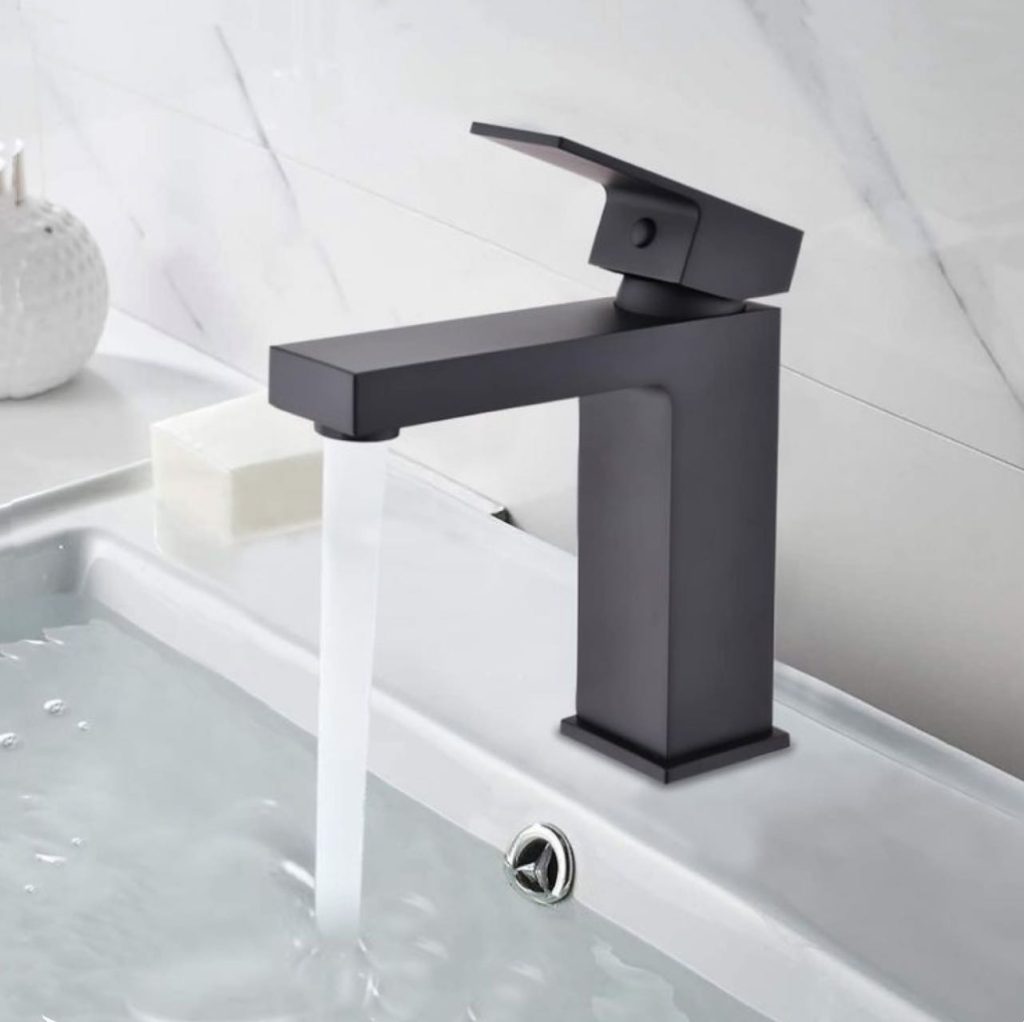 Modern black faucet with running water in a bathroom sink.
