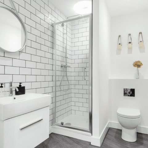 Modern bathroom with white tiles, shower, sink, and toilet.