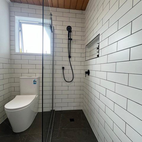 Modern bathroom with white subway tiles, glass shower, and window.