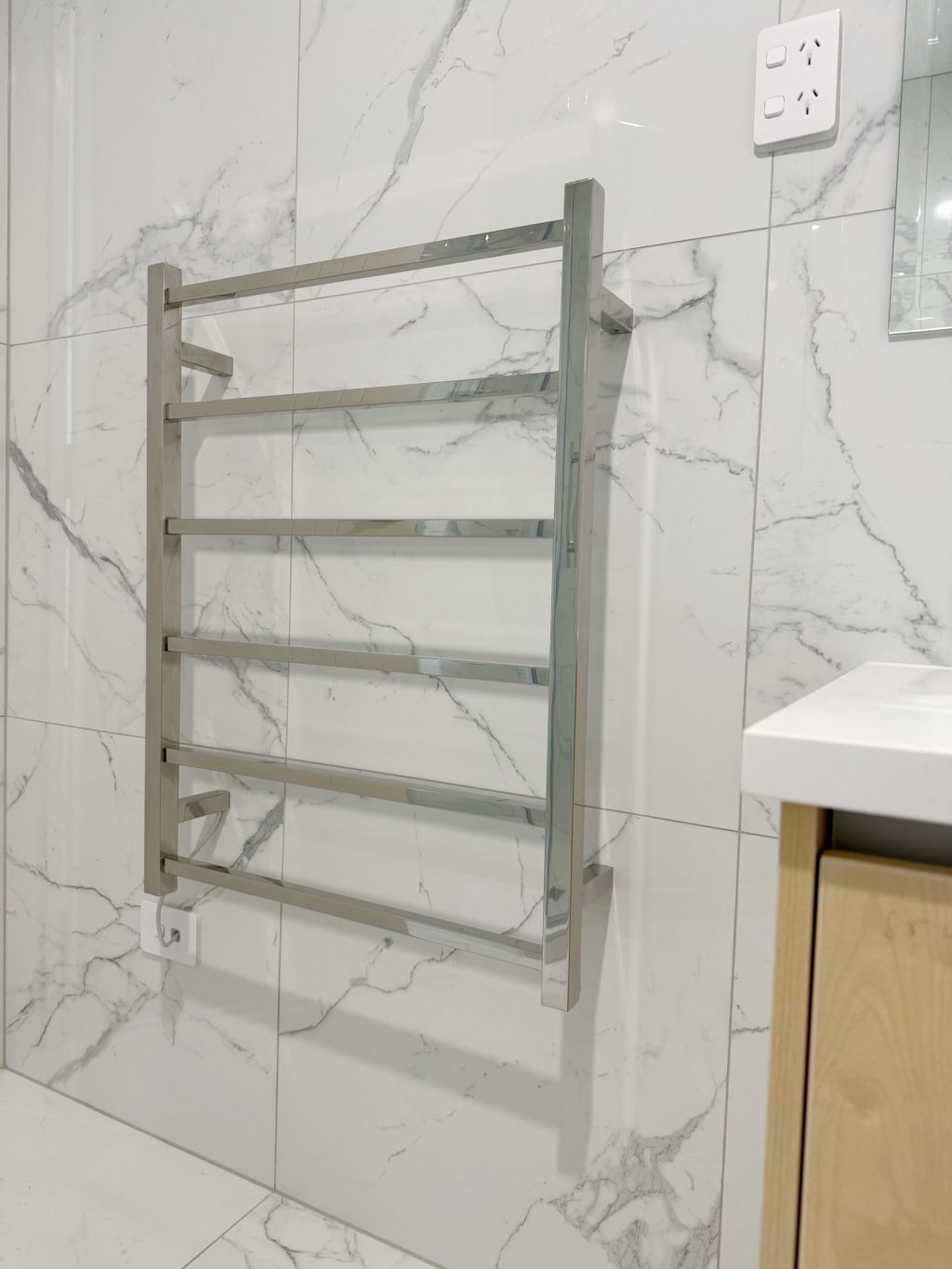 Chrome towel rack on marble bathroom wall.