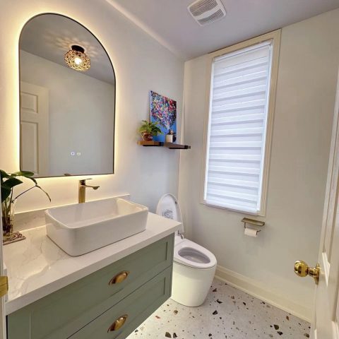 Modern bathroom with vessel sink, oval mirror, and terrazzo floor.