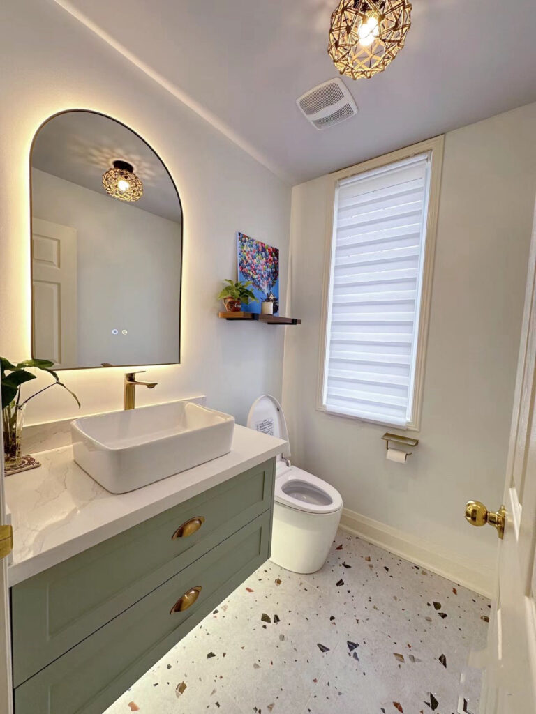 Modern bathroom with vessel sink, oval mirror, and terrazzo floor.
