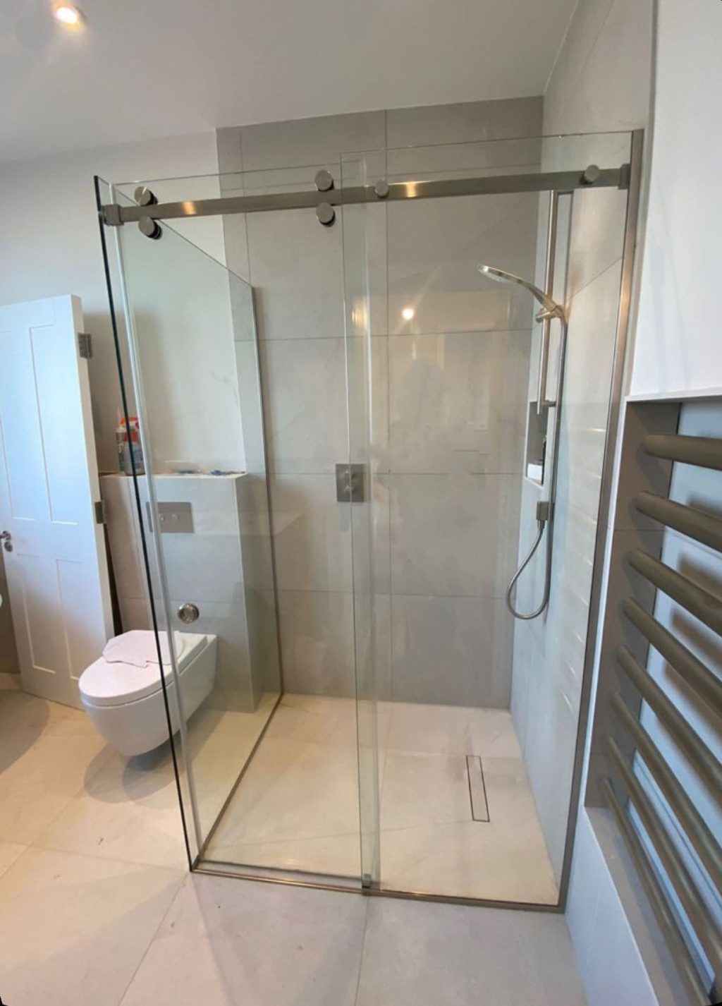 Glass shower enclosure with sliding door in modern bathroom.