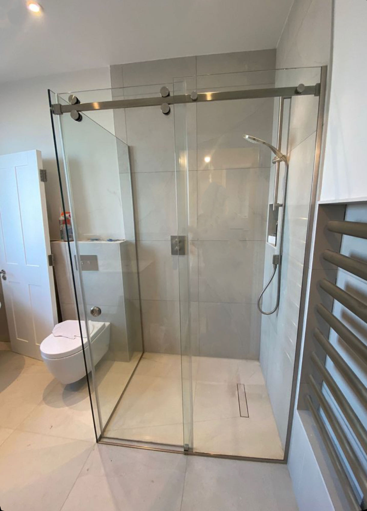 Glass shower enclosure with sliding door in modern bathroom.
