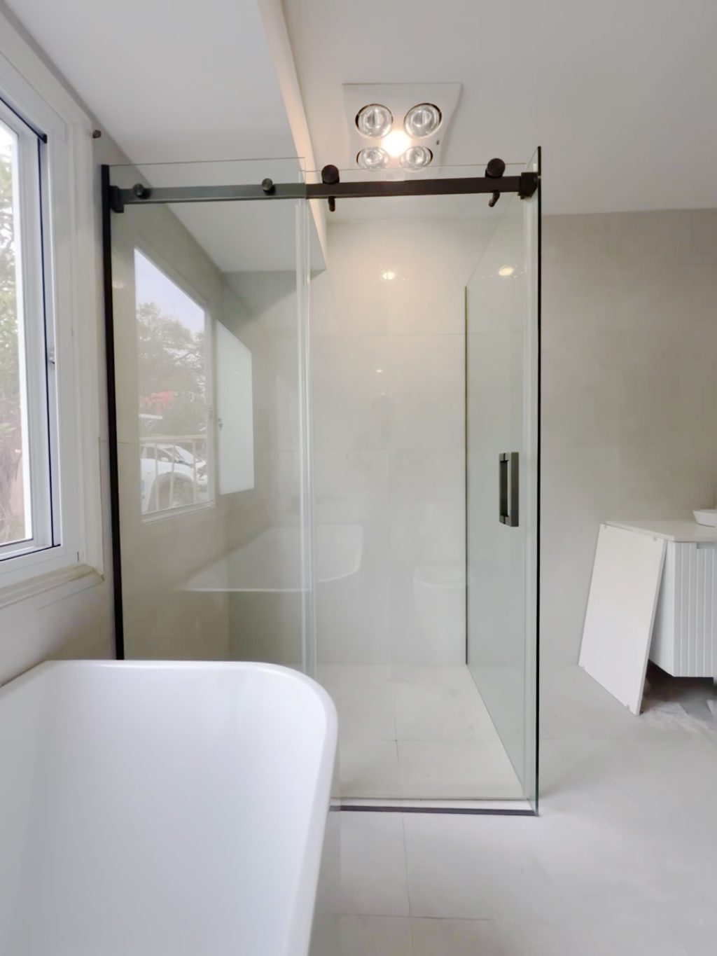 Modern bathroom with glass shower enclosure and white bathtub.