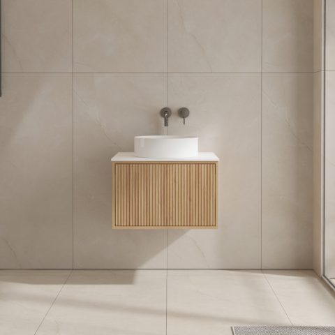 Modern bathroom with wooden vanity and round white sink against tiled wall.