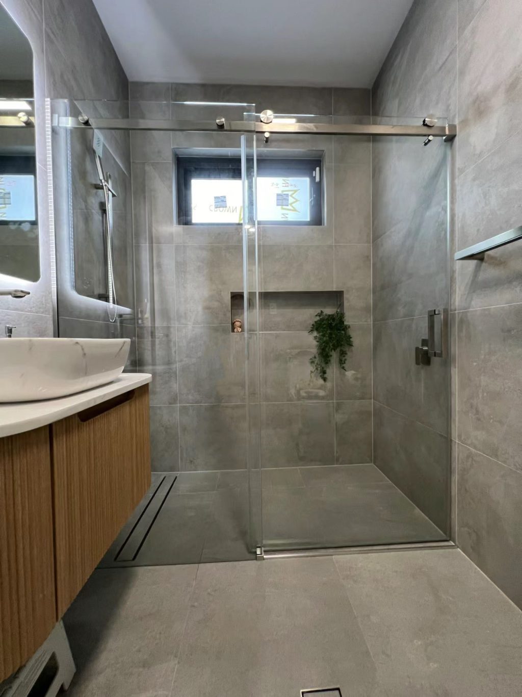 Modern bathroom with glass shower door and wooden vanity.