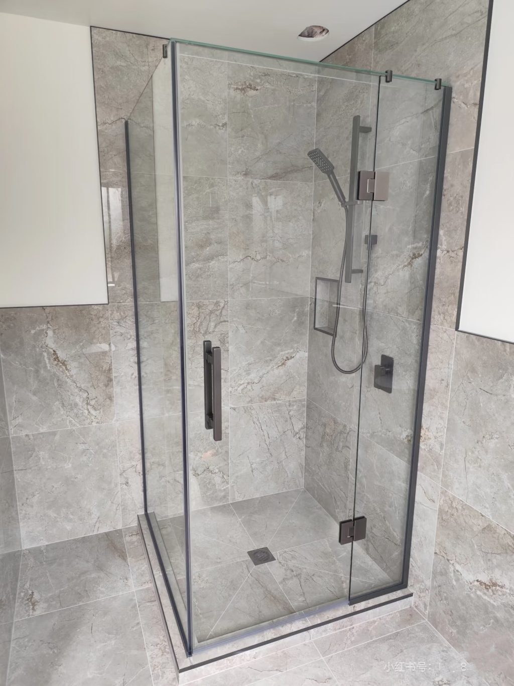Glass shower enclosure with marble walls and modern fixtures.